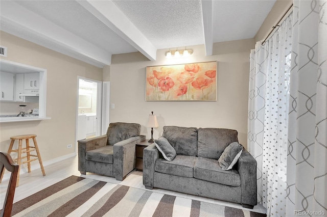 living room featuring beam ceiling, a textured ceiling, and washer / clothes dryer