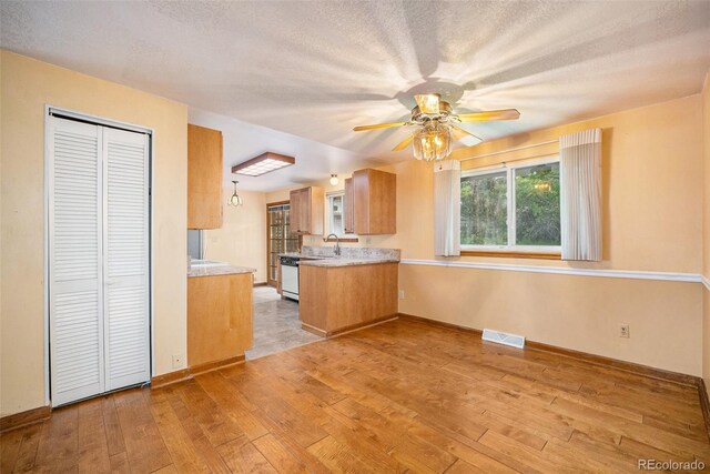 8269 Zephyr St, Arvada, CO 80005 - kitchen featuring light wood-type flooring, a ceiling fan, light countertops, a sink, and brown cabinetry