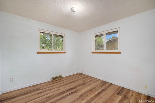 8269 Zephyr St, Arvada, CO 80005 - unfurnished room with plenty of natural light, light wood finished floors, baseboards, and a textured ceiling