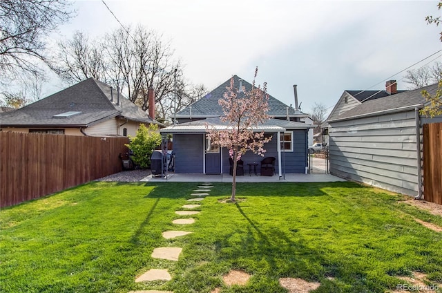 rear view of house with a fenced backyard, a gate, a lawn, and a patio area