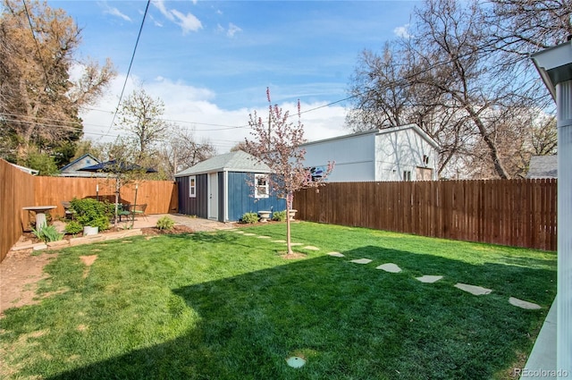 view of yard featuring an outdoor structure, a fenced backyard, and a storage unit