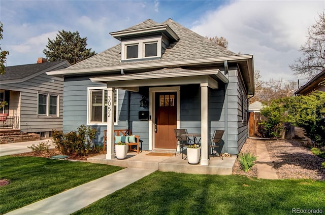 bungalow-style house with a front lawn, roof with shingles, and fence