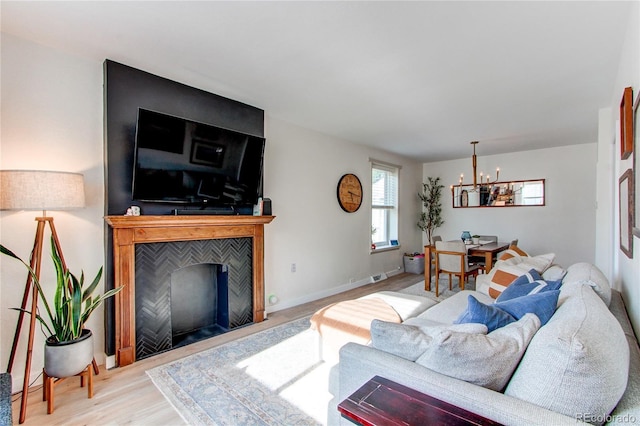 living area featuring a fireplace with flush hearth, an inviting chandelier, plenty of natural light, and wood finished floors