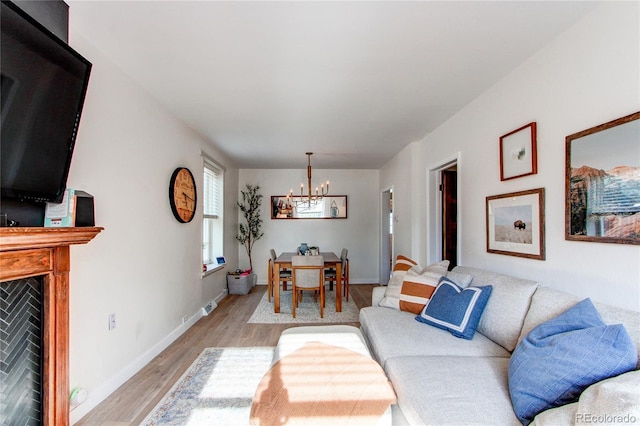 living room with baseboards, light wood finished floors, and a chandelier