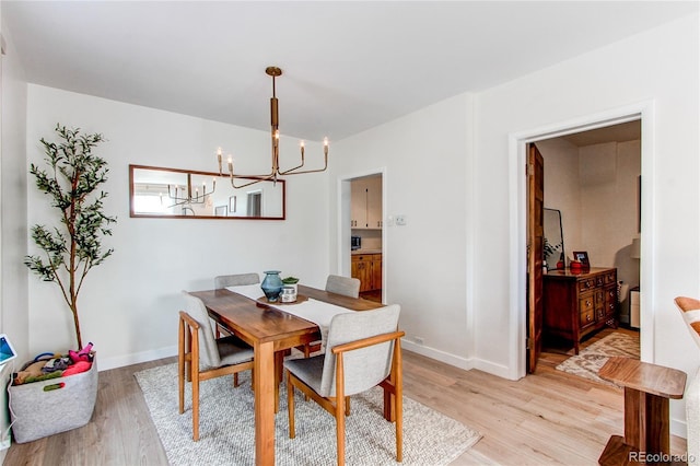 dining area featuring baseboards, a chandelier, and light wood finished floors
