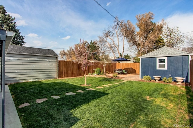view of yard featuring a patio, an outbuilding, and a fenced backyard