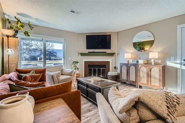 living room featuring a textured ceiling, a fireplace, and light hardwood / wood-style flooring