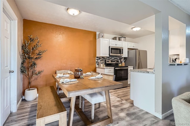 dining area with white cabinetry and light wood-type flooring