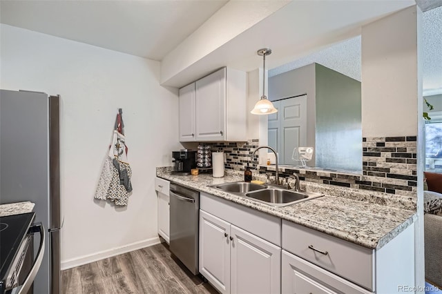 kitchen with white cabinetry, sink, decorative backsplash, hanging light fixtures, and stainless steel appliances