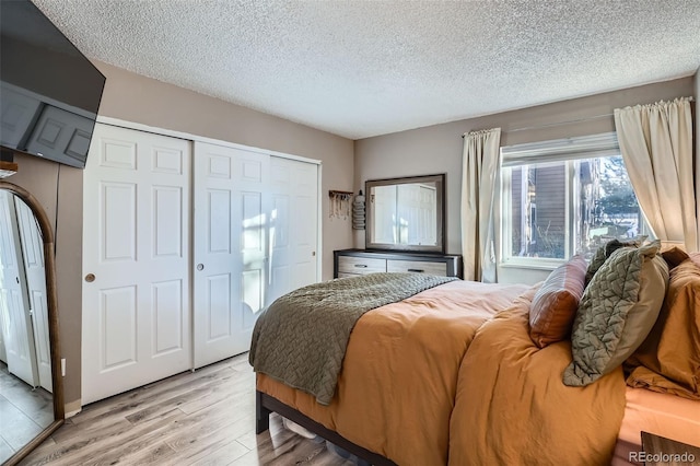 bedroom featuring a closet, a textured ceiling, and light wood-type flooring