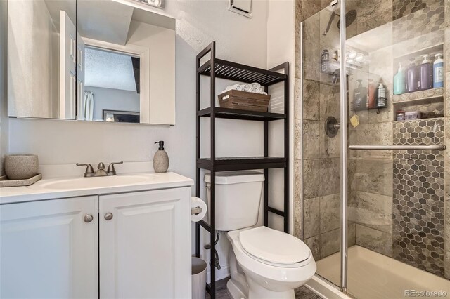 bathroom with vanity, a shower with shower door, and toilet