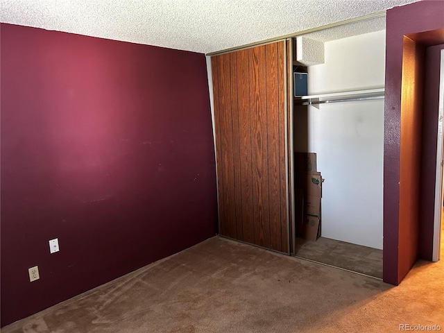 unfurnished bedroom with carpet flooring, a textured ceiling, and a closet