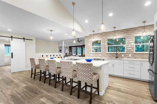 14960 Spiritwood Loop, Elbert, CO 80106 - kitchen featuring a barn door, light wood-style floors, white cabinets, recessed lighting, and freestanding refrigerator