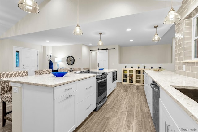 14960 Spiritwood Loop, Elbert, CO 80106 - kitchen with stainless steel appliances, a barn door, light wood-type flooring, white cabinets, and recessed lighting