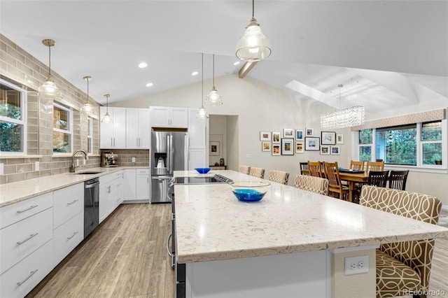 14960 Spiritwood Loop, Elbert, CO 80106 - kitchen with stainless steel appliances, light wood-style flooring, a center island, tasteful backsplash, and white cabinetry