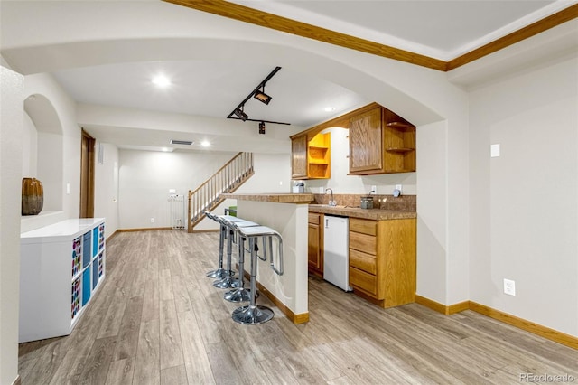 14960 Spiritwood Loop, Elbert, CO 80106 - kitchen featuring white dishwasher, open shelves, light wood-style flooring, brown cabinetry, and a breakfast bar