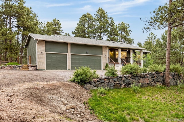 14960 Spiritwood Loop, Elbert, CO 80106 - view of front facade with brick siding, a porch, dirt driveway, and an attached garage