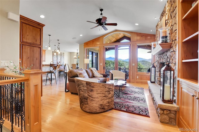 1007 Nob Hill Rd, Evergreen, CO 80439 - living room featuring a fireplace, a ceiling fan, light wood finished floors, vaulted ceiling, and a mountain view