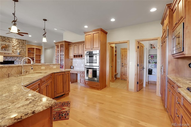 1007 Nob Hill Rd, Evergreen, CO 80439 - kitchen featuring stainless steel appliances, a ceiling fan, light wood-style floors, tasteful backsplash, and brown cabinets
