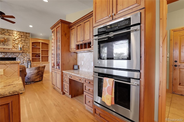 1007 Nob Hill Rd, Evergreen, CO 80439 - kitchen featuring stainless steel double oven, brown cabinetry, a ceiling fan, light stone countertops, and recessed lighting