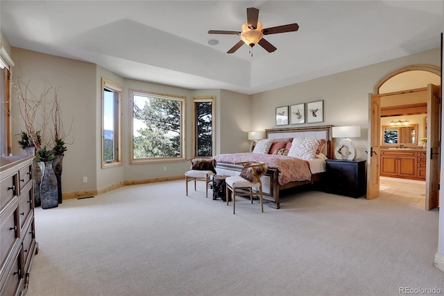 1007 Nob Hill Rd, Evergreen, CO 80439 - bedroom with light colored carpet, a tray ceiling, a sink, baseboards, and connected bathroom