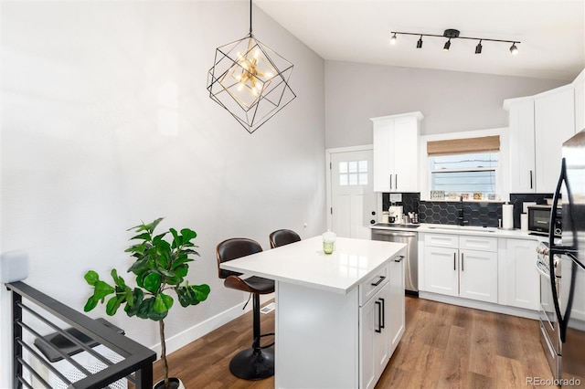 4800 S Tabor St, Morrison, CO 80465 - kitchen with stainless steel dishwasher, a kitchen breakfast bar, tasteful backsplash, rail lighting, and light countertops