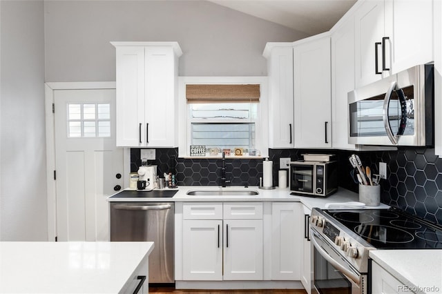 4800 S Tabor St, Morrison, CO 80465 - kitchen featuring stainless steel appliances, light countertops, white cabinetry, backsplash, and vaulted ceiling