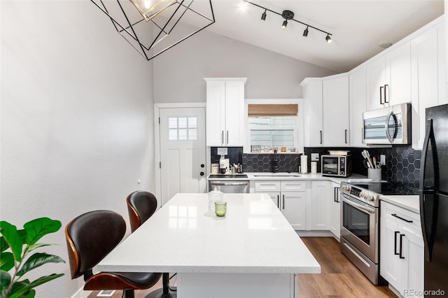 4800 S Tabor St, Morrison, CO 80465 - kitchen with stainless steel appliances, a kitchen breakfast bar, backsplash, lofted ceiling, and a center island