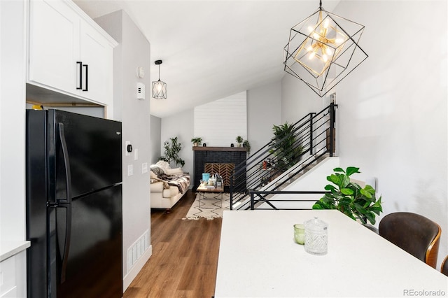 4800 S Tabor St, Morrison, CO 80465 - dining space with vaulted ceiling, wood finished floors, a chandelier, and a brick fireplace