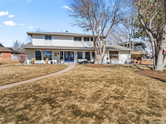 back of property with covered porch and a lawn