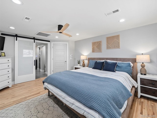 6111 W Fremont Dr, Littleton, CO 80128 - bedroom featuring a barn door, wood finished floors, recessed lighting, and ceiling fan