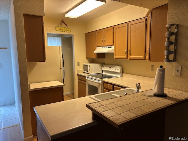 kitchen featuring sink, white appliances, and kitchen peninsula