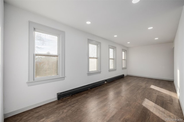 spare room featuring plenty of natural light, dark hardwood / wood-style floors, and a baseboard radiator