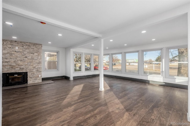 unfurnished living room with beam ceiling, a stone fireplace, a baseboard heating unit, and dark wood-type flooring