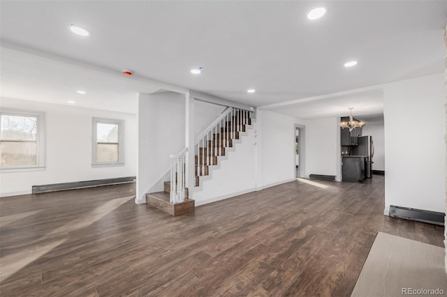 unfurnished living room with a chandelier, dark wood-type flooring, and a baseboard heating unit