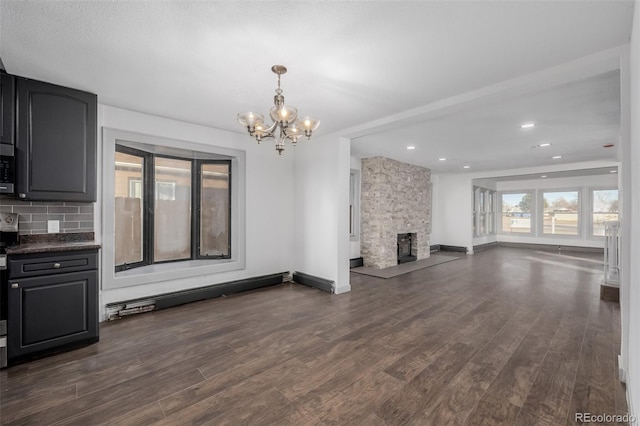 unfurnished living room with a fireplace, dark hardwood / wood-style floors, and an inviting chandelier