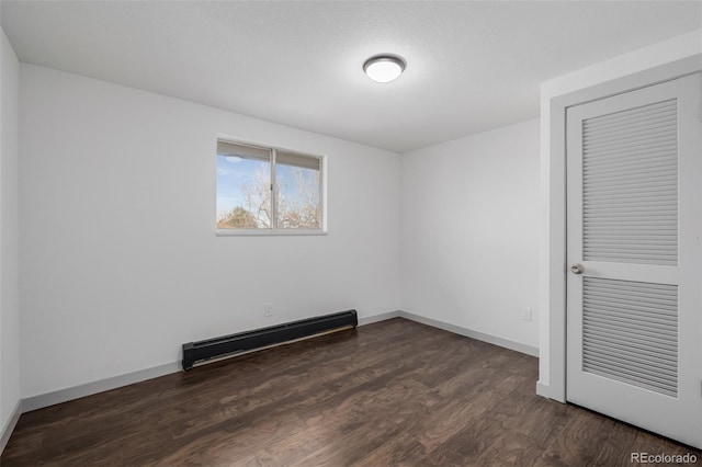 spare room featuring a baseboard radiator and dark wood-type flooring