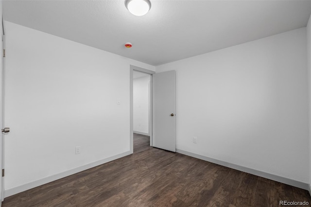 unfurnished room with dark wood-type flooring