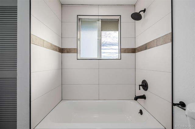 bathroom featuring tiled shower / bath combo and toilet