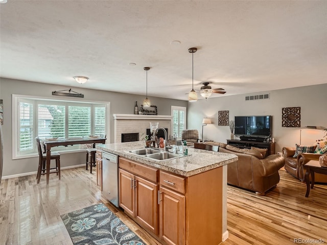 3265 W 11th Avenue Ct, Broomfield, CO 80020 - kitchen with dishwasher, a sink, open floor plan, a brick fireplace, and light wood-style floors