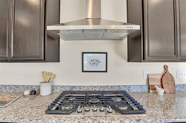 kitchen with dark brown cabinetry, wall chimney range hood, and stainless steel gas stovetop