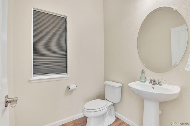 bathroom featuring a sink, toilet, wood finished floors, and baseboards