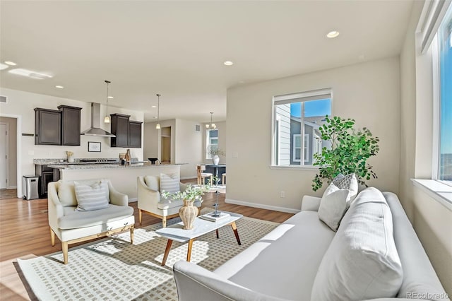 living area with light wood-type flooring, baseboards, and recessed lighting