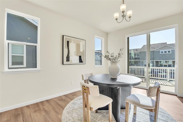 dining room featuring light wood-style flooring, baseboards, plenty of natural light, and a notable chandelier