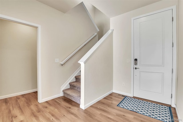 foyer entrance featuring light wood-type flooring, baseboards, visible vents, and stairs