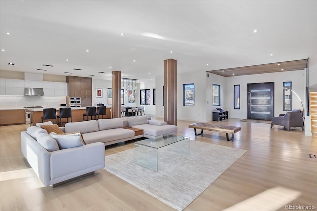 living area featuring recessed lighting, stairway, and light wood finished floors