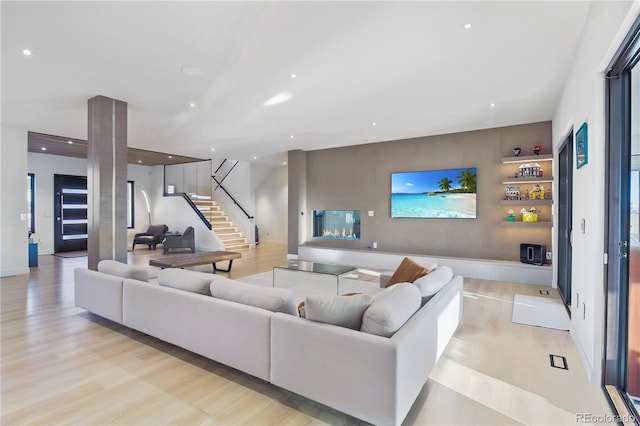 living room featuring recessed lighting, stairway, baseboards, and light wood-style flooring