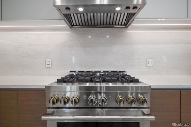interior details featuring light countertops, extractor fan, stainless steel range with gas stovetop, and modern cabinets