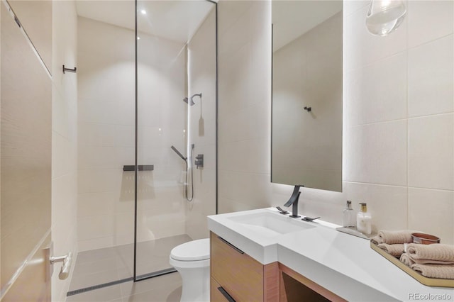 bathroom featuring tile patterned floors, vanity, tile walls, toilet, and a walk in shower