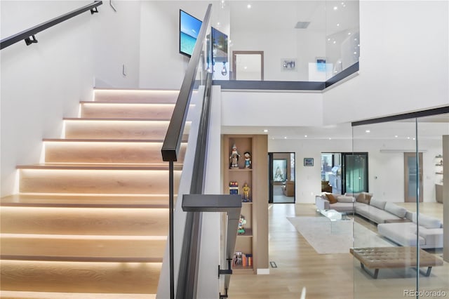 staircase with wood finished floors and a high ceiling